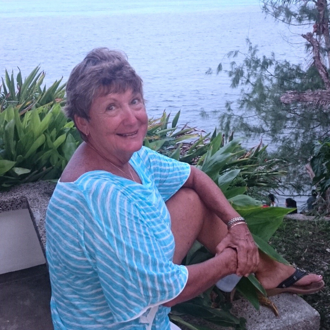 woman sitting on stone wall looking at camera with smile