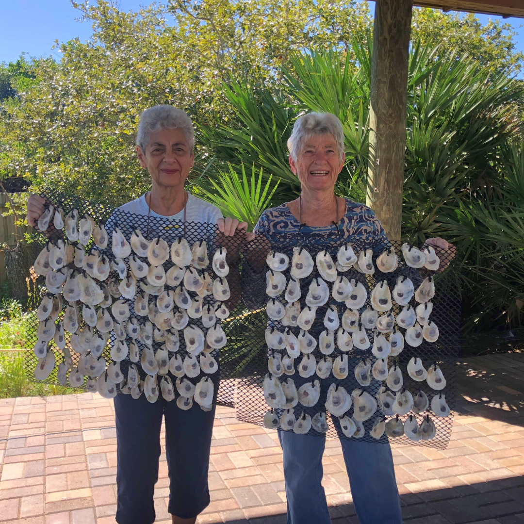 two women standing holding oyster mats