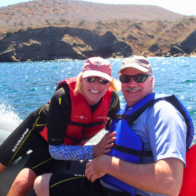 older man and woman hugging while on boat overlooking water and mountains