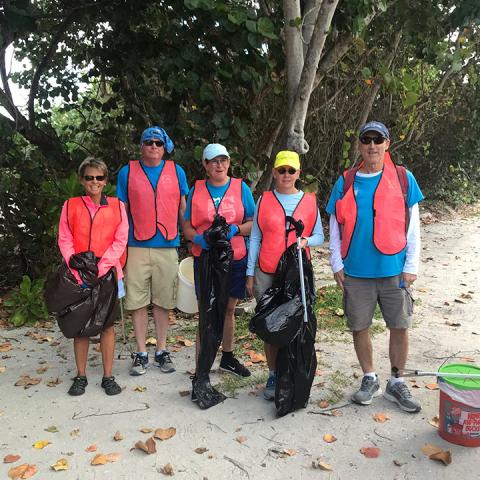 people standing in a group o the side of the road with bags of trash